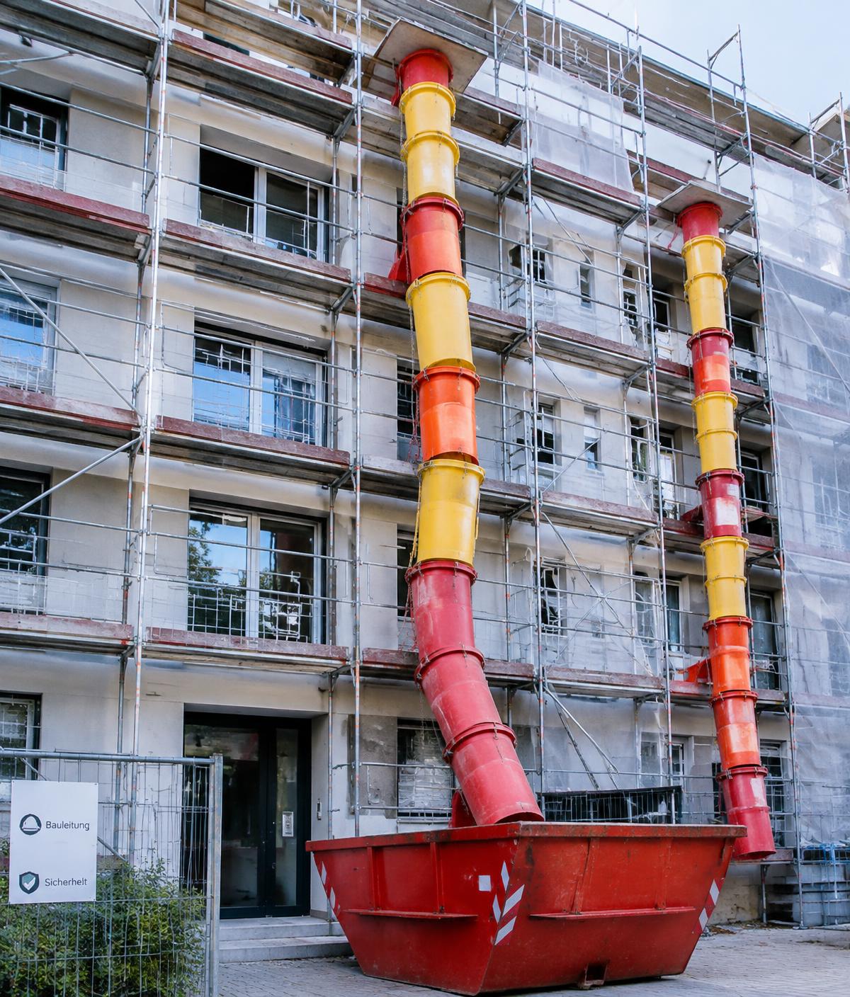 Cevi za šut postavljene na fasadi zgrade iznad kontejnera